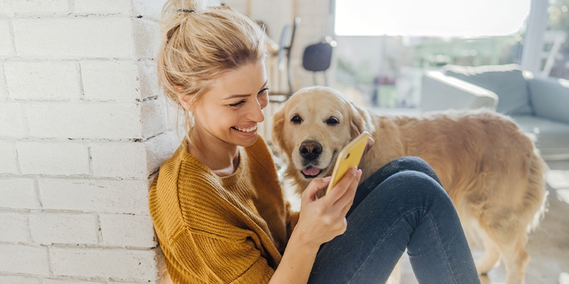 woman sitting on floor with her golden retriever looking at her phone